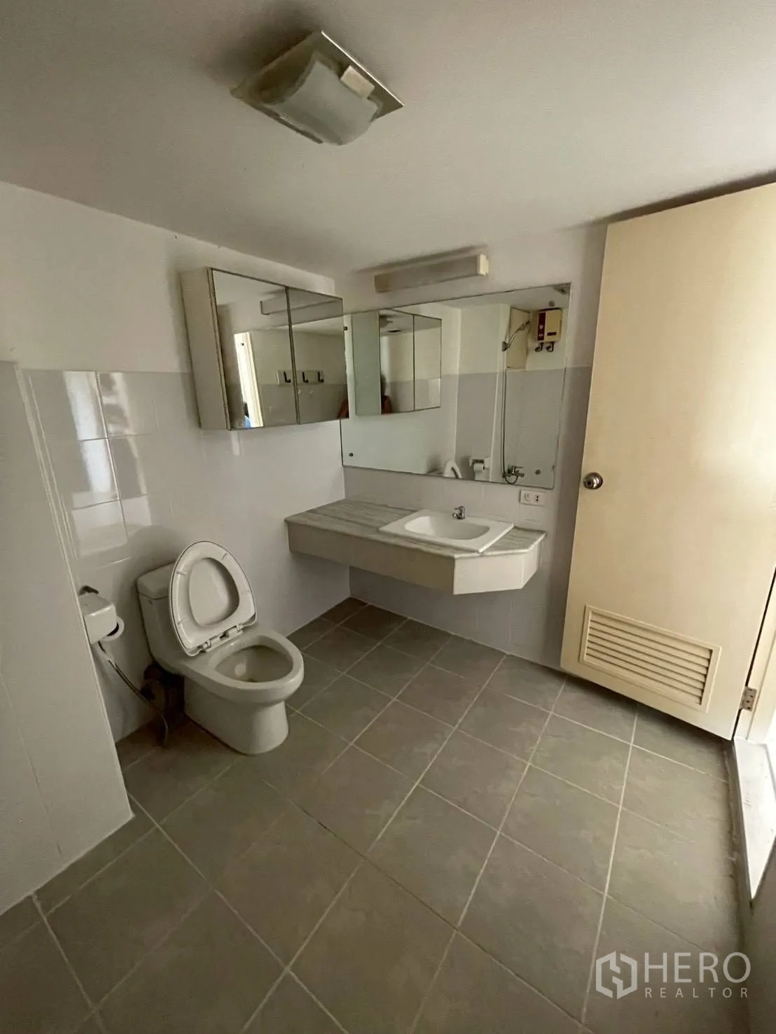 Condominium for sale in Wang Thonglang, Bangkok - Clean bathroom with large vanity, toilet and mirrored cabinets.