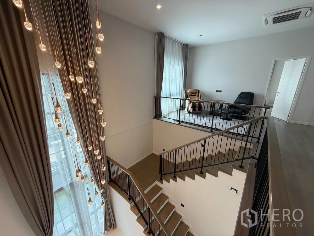 独立式住宅 出租或出售在Bang Phli, Samut Prakan - 二层楼梯旁休闲区，戏剧化吊灯与充沛自然光。