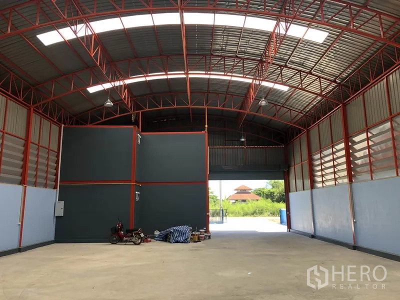 货栈 出租或出售在Sai Noi, Nonthaburi - 由内向入口卷闸门的视角，通透无柱空间与侧墙通风板。