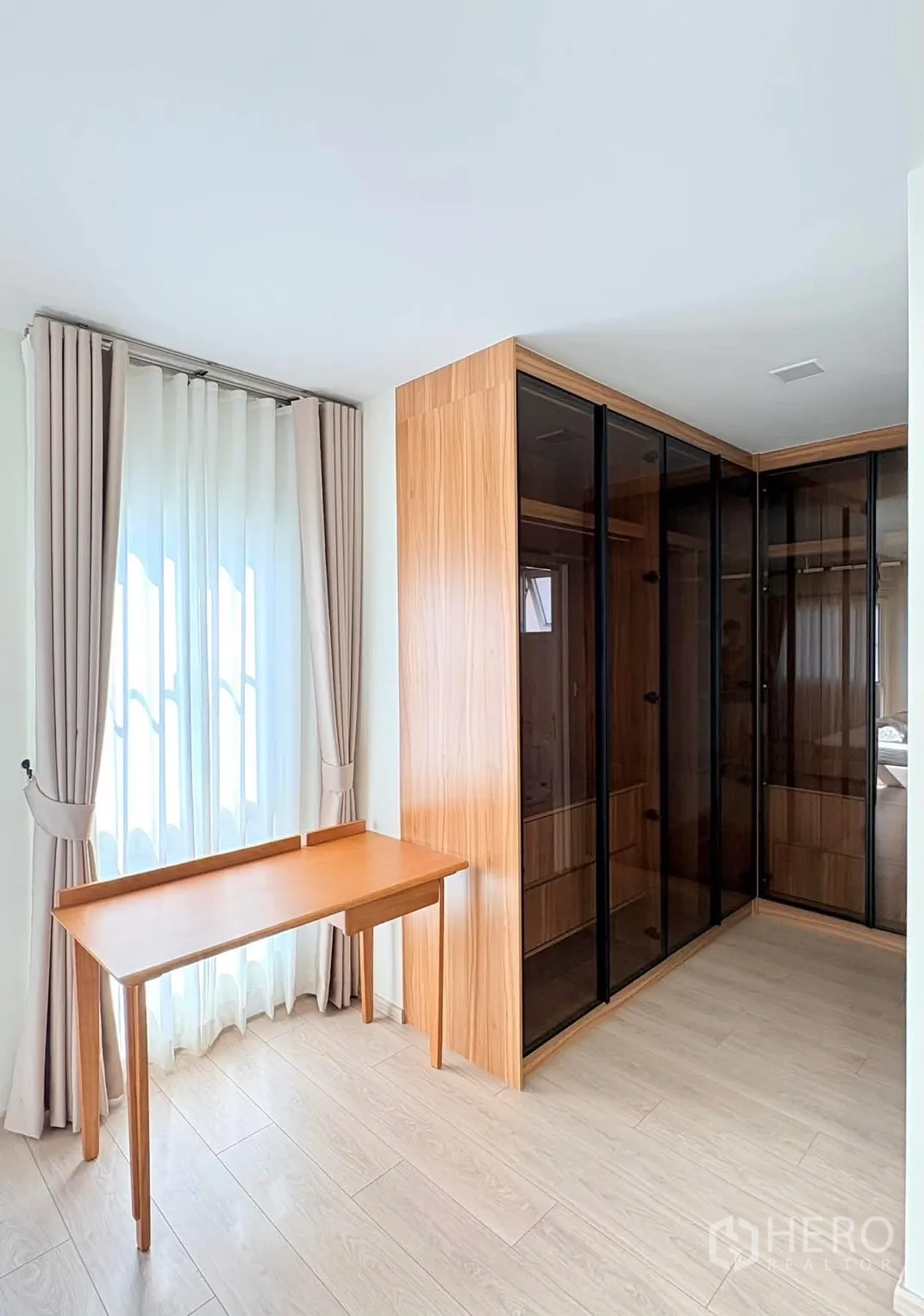 独立式住宅 for rent in Bang Phli, Samut Prakan - 明亮更衣角，L形玻璃衣柜、木质书桌与窗帘。