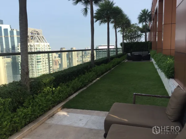 公寓 出租或出售在Bang Rak, Bangkok - 空中花园草坪配棕榈与休闲座位，远眺高楼景色。