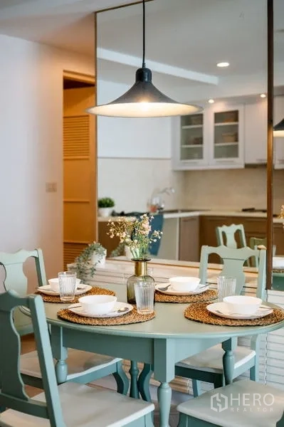 Condominium for sale in Watthana, Bangkok - Cozy round dining table set under a pendant lamp with tableware and a mirror wall.