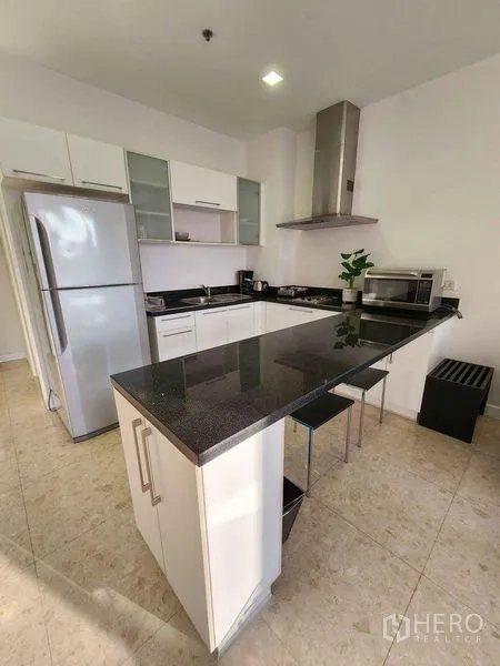 Condominium for rent in Khlong Toei, Bangkok - Contemporary kitchen with granite breakfast bar, stainless refrigerator and range hood.