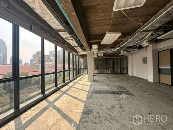 办公空间 出租 - 转角开放式办公室，整面落地窗与曼谷天际线景观，外露天花与风管。