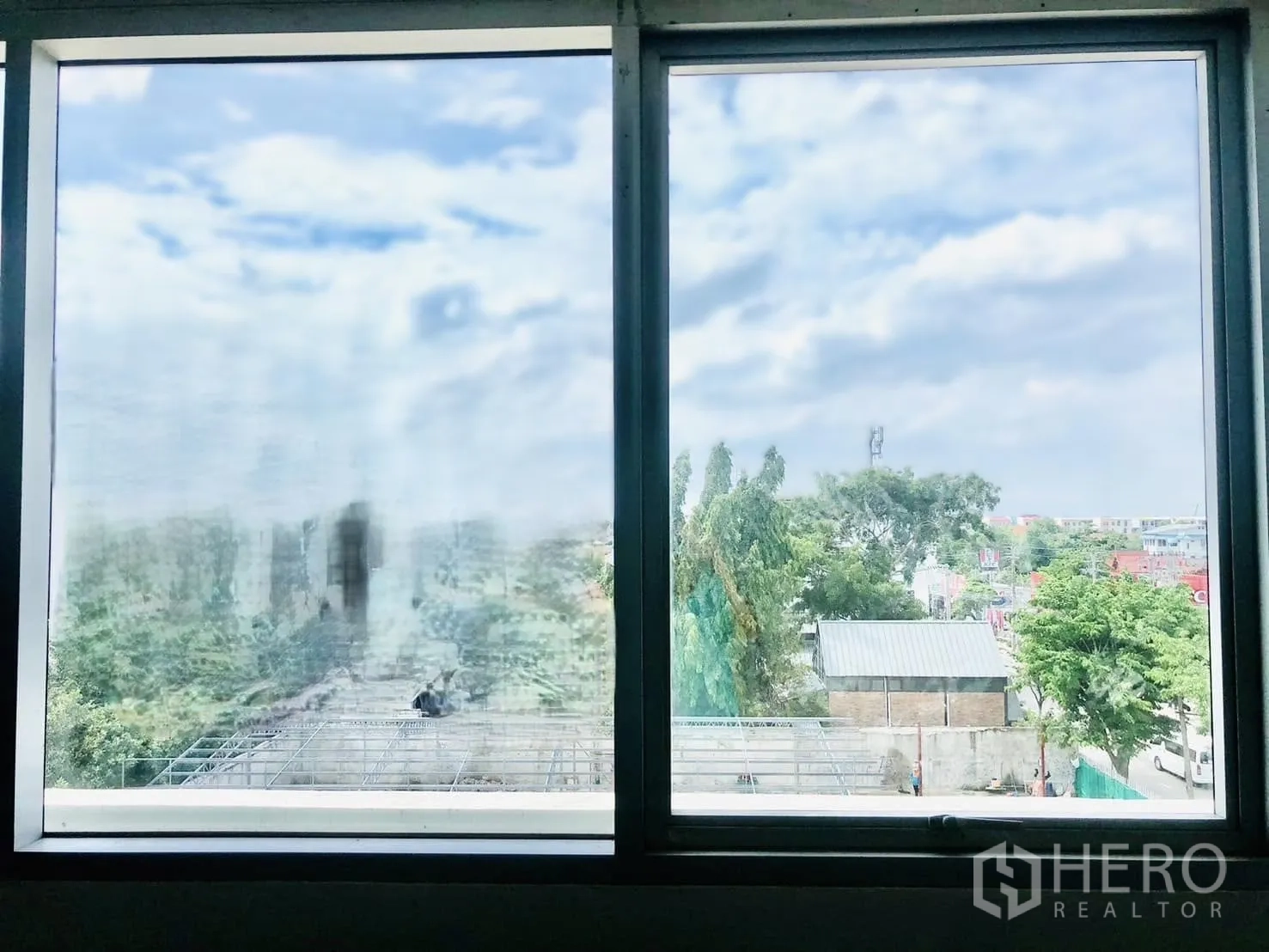 Office Space for rent in Lat Phrao, Bangkok - Two-pane window view over trees and low-rise buildings under a blue sky.