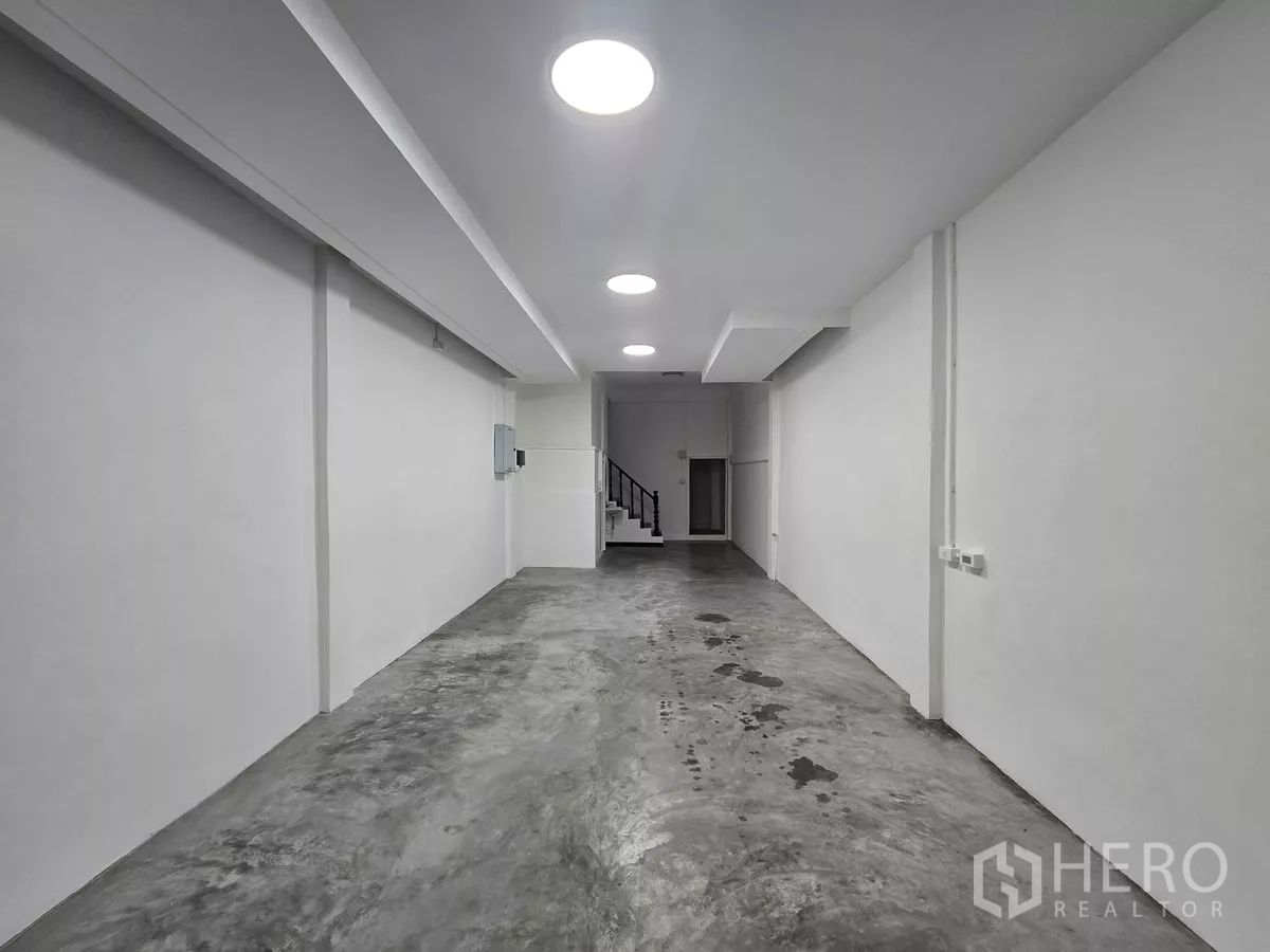店屋 出租在Watthana, Bangkok - 明亮的混凝土地面走廊，嵌灯与后方楼梯