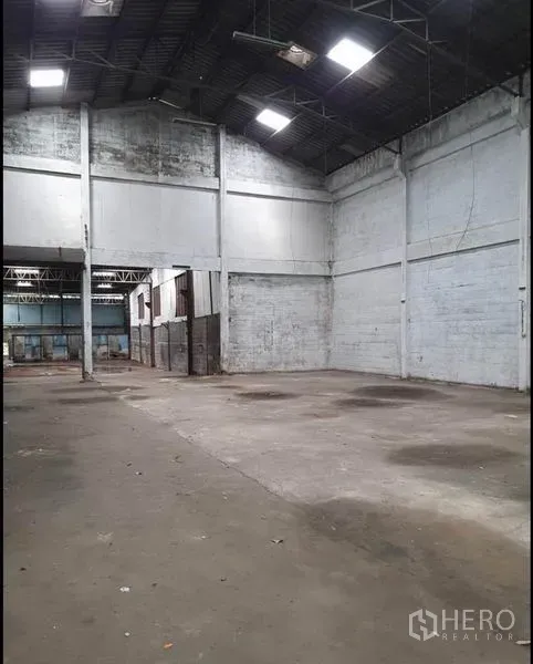Warehouse for rent in Phra Samut Chedi, Samut Prakan - Open storage zone with tall walls, concrete slab and roof lights providing natural illumination.