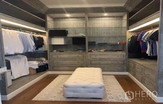 Detached House for sale in Bang Phli, Samut Prakan - Large walk-in closet with built-in wardrobes, drawers, and a central upholstered ottoman.