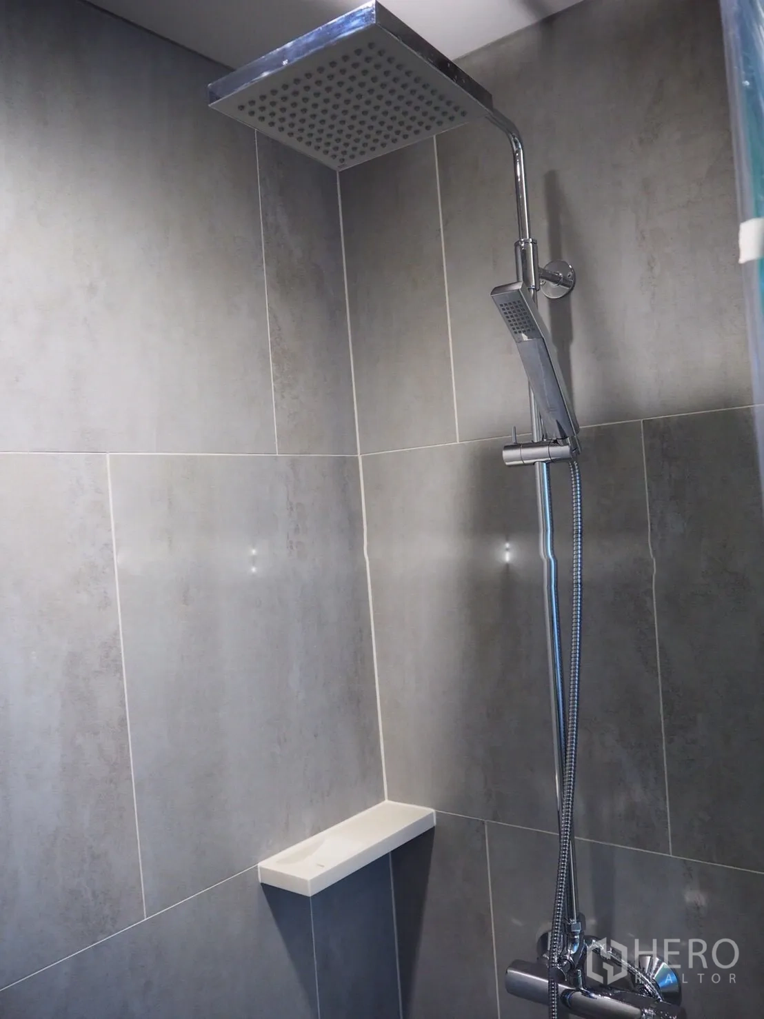 Condominium for rent in Khlong Toei, Bangkok - Walk-in shower with chrome rain shower head and gray tiled walls.