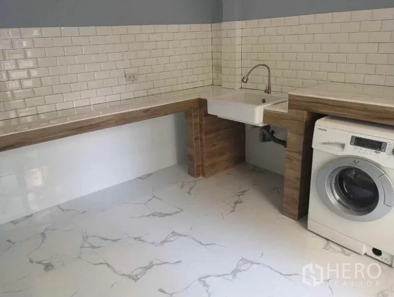 Detached House for rent in Wang Thonglang, Bangkok - Laundry room with white subway tiles, farmhouse sink, wood-trim counters, and washing machine.