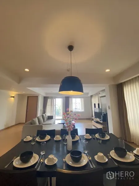 房间 出租在Watthana, Bangkok - 从餐桌望向客厅，设沙发、电视柜和带窗帘的大窗户。