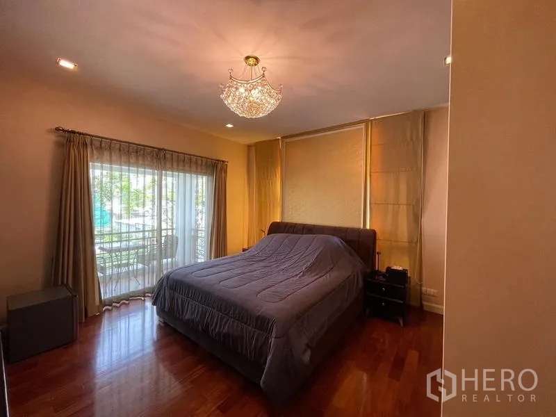 บ้าน ขายในLat Krabang, Bangkok - ห้องนอนหลักพื้นไม้ มีแชนเดอเลียร์ และทางออกสู่ระเบียงส่วนตัว