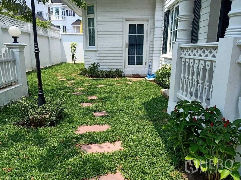 独立式住宅 出租在Bang Na, Bangkok - 私家庭院草坪，踏石小径与白色围栏。
