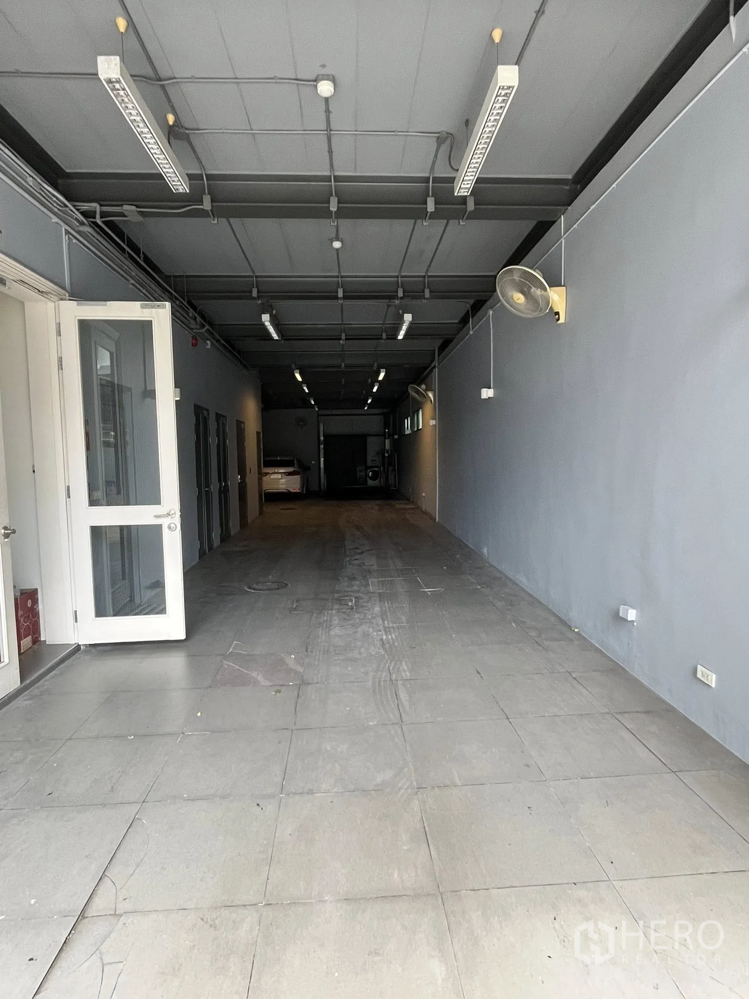 Home Office for rent in Watthana, Bangkok - Covered drive-in or indoor parking bay with high ceiling and strip lighting.