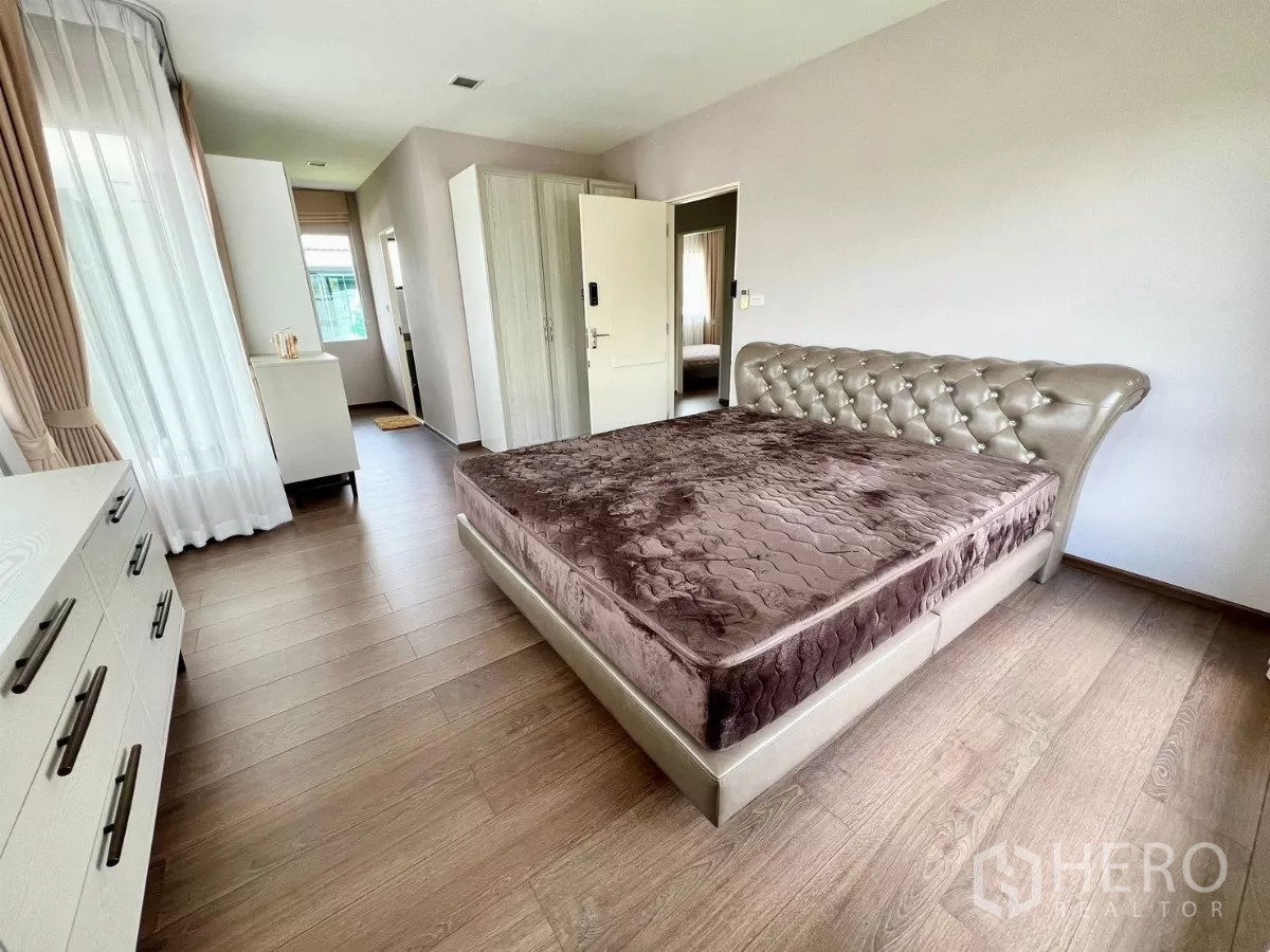 Detached House for rent or sale in Bang Phli, Samut Prakan - Spacious master bedroom with tufted bed, wood floors and access to ensuite area.