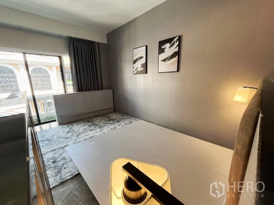 Home Office for rent in Watthana, Bangkok - Cozy bedroom corner with a large window, rug and modern wall art.