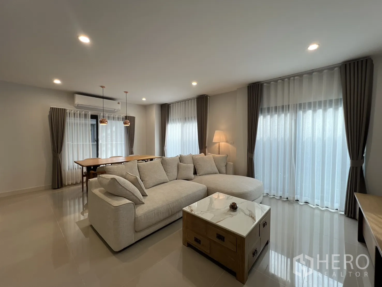 Detached House for rent in Prawet, Bangkok - Bright open-plan living room with beige sectional and dining table.