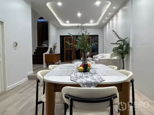 Townhouse for rent - Dining space with a long table, indoor greenery and a view toward the entry and staircase.