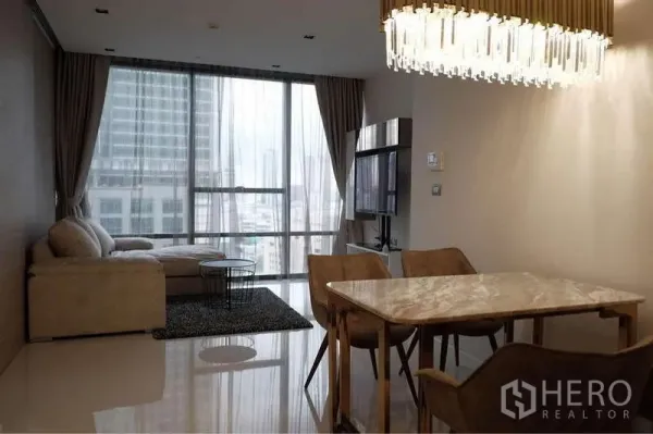 Condominium for rent in Sathon, Bangkok - Living room and dining space with L-shaped sofa, TV console and city-view windows.