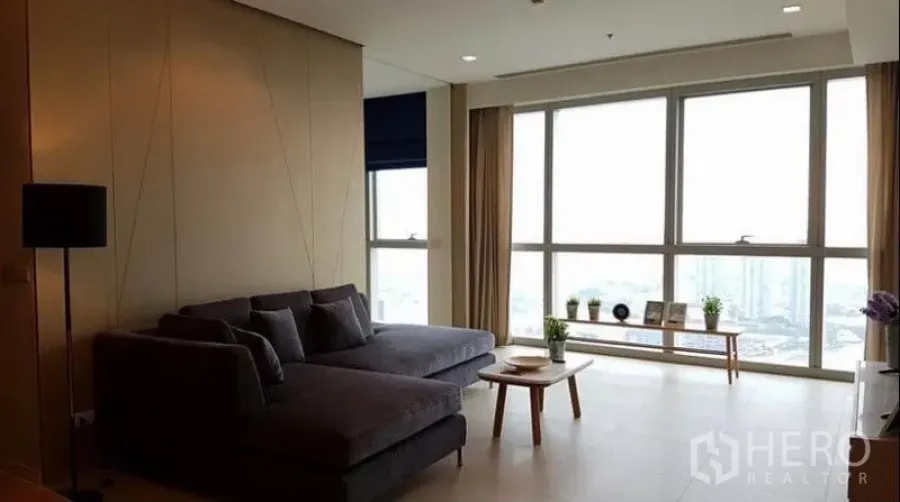 คอนโด ให้เช่าในKhlong San, Bangkok - ห้องนั่งเล่นโปร่ง กระจกพื้นจรดเพดาน โซฟาตัวแอล วิวแม่น้ำและเมือง