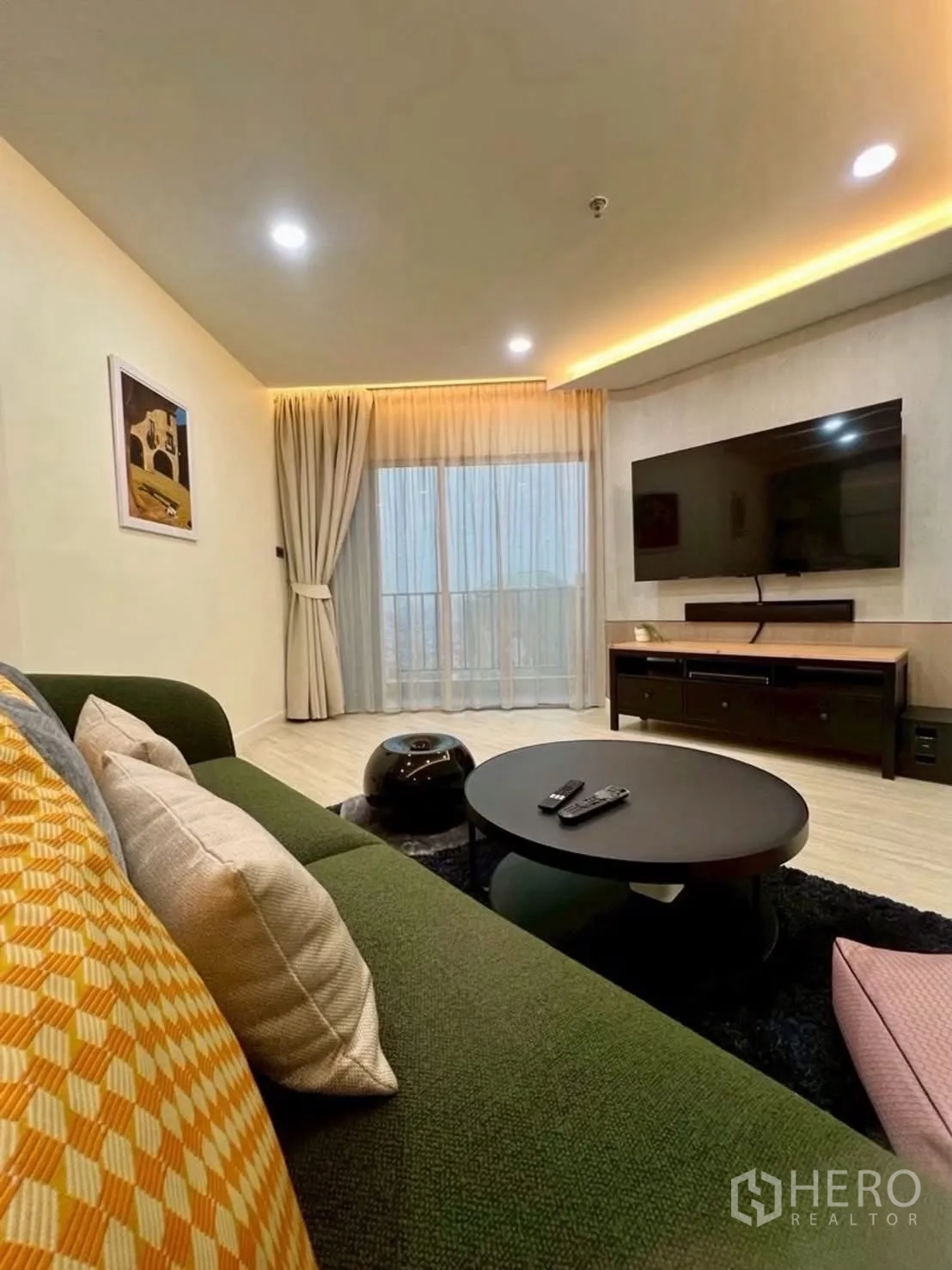 Condominium for rent in Huai Khwang, Bangkok - Living area with TV, coffee table, and full-height curtains.