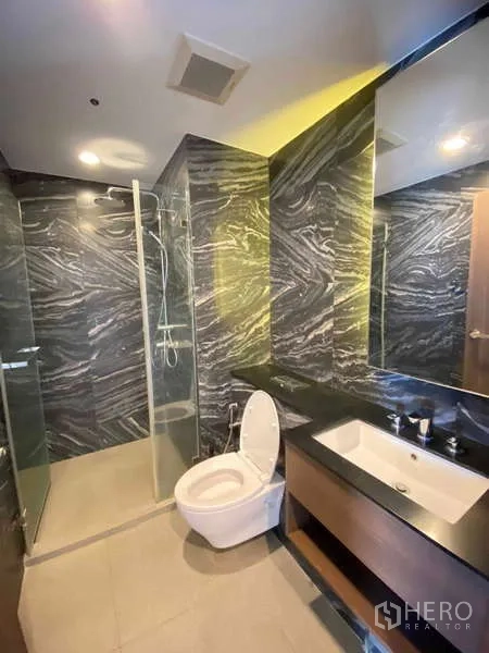 Condominium for rent - Second bathroom featuring glass shower, marble‑pattern tiles and wide countertop basin.