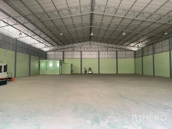 Warehouse for rent in Bang Phli, Samut Prakan - Open warehouse floor with high ceiling, side ventilation, and a small glass office room at the rear.
