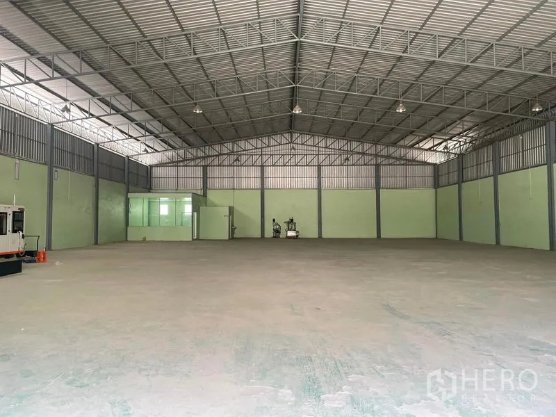 Warehouse for rent in Bang Phli, Samut Prakan - Open warehouse floor with high ceiling, side ventilation, and a small glass office room at the rear.