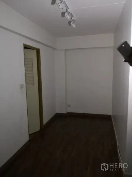 Office Space for rent in Khlong Toei, Bangkok - Compact private room with dark wood floors and ceiling spotlights.