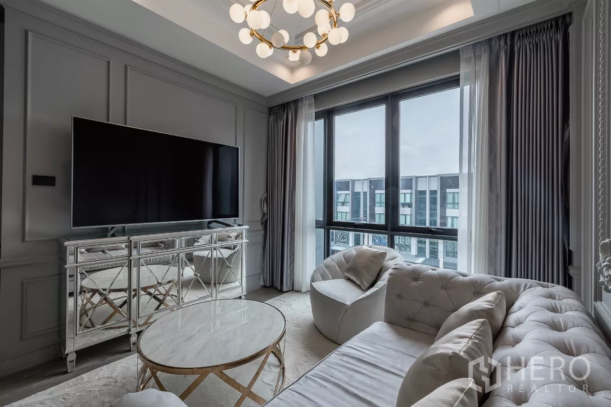 Home Office for sale in Don Mueang, Bangkok - Elegant living lounge with tufted sofa, chandelier, large TV and wide windows overlooking the complex.