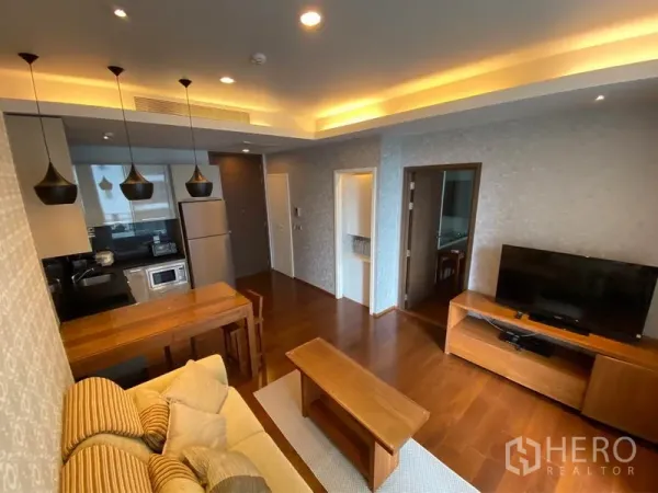 公寓 出租或出售在Watthana, Bangkok - 客厅设电视柜与吊顶灯，旁有紧凑厨房面向休闲区。