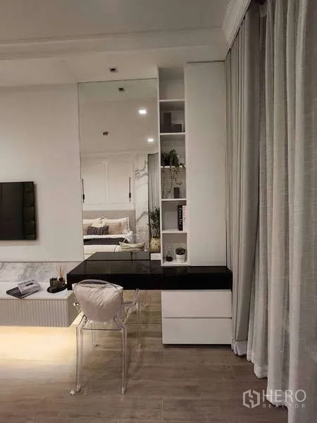 Condominium for sale in Watthana, Bangkok - Built-in work desk with mirror and shelving beside floor-to-ceiling drapes.