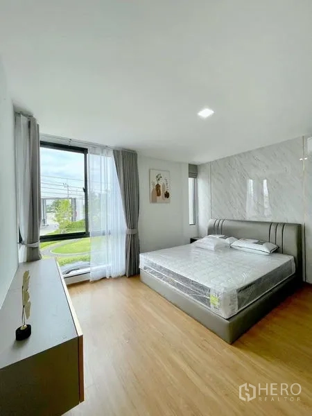 Townhouse for rent in Bang Phli, Samut Prakan - Sunlit master bedroom with large window, king bed and wood flooring.