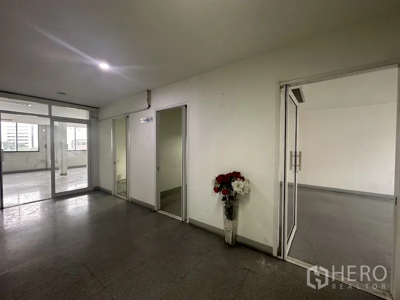 Office Space for rent in Khlong Toei, Bangkok - Common corridor with glass doors, separate rooms and a decorative vase.