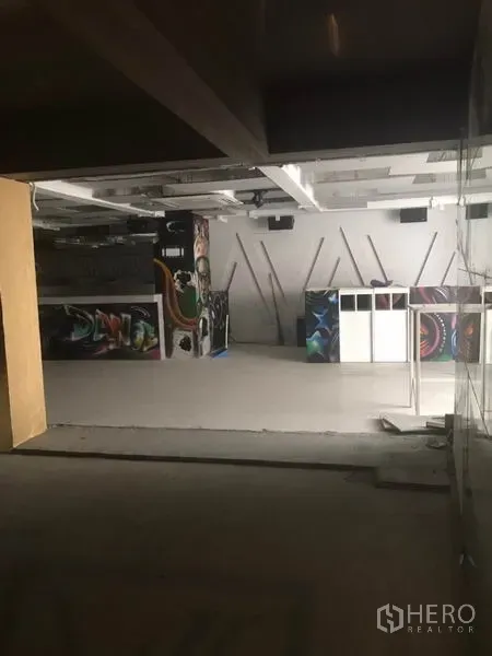 零售空间 出租在Khlong Toei, Bangkok - 室内零售空间，白色天花，带吧台与涂鸦装饰面板，地面平整，布局灵活。