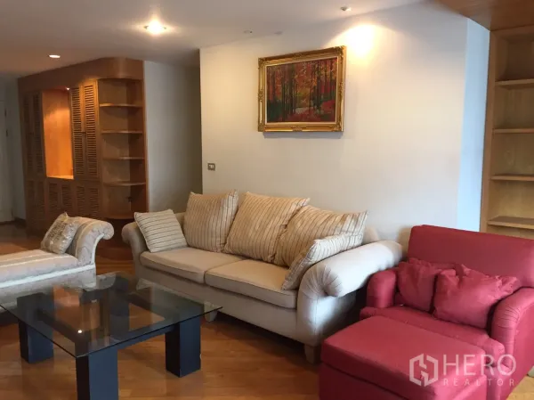 คอนโด ให้เช่าในPathum Wan, Bangkok - ห้องนั่งเล่นอบอุ่น โซฟาสีครีม เก้าอี้สีแดง โต๊ะกลางกระจก และชั้นไม้บิวท์อิน บนพื้นไม้