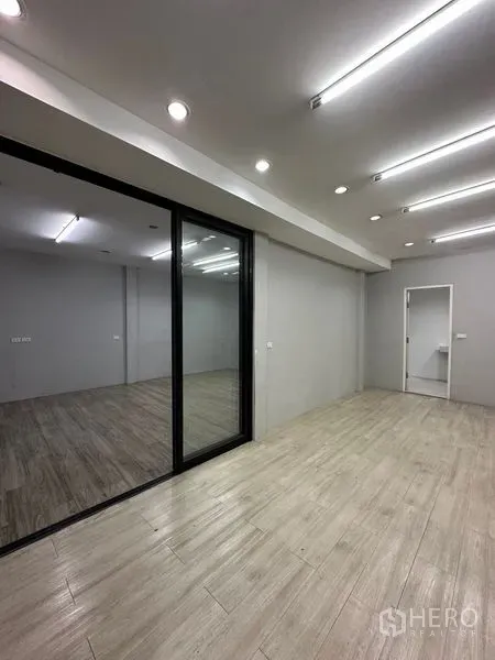 零售空间 出租在Khlong Toei, Bangkok - 明亮的零售单元，木纹地砖、筒灯、玻璃隔断与通往后区的门。