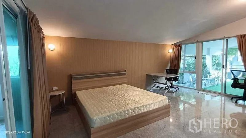 บ้าน ให้เช่าในLam Luk Ka, Pathum Thani - ห้องนอนขนาดใหญ่ มีเตียง โต๊ะทำงาน และประตูกระจกบานเลื่อนสู่ระเบียง