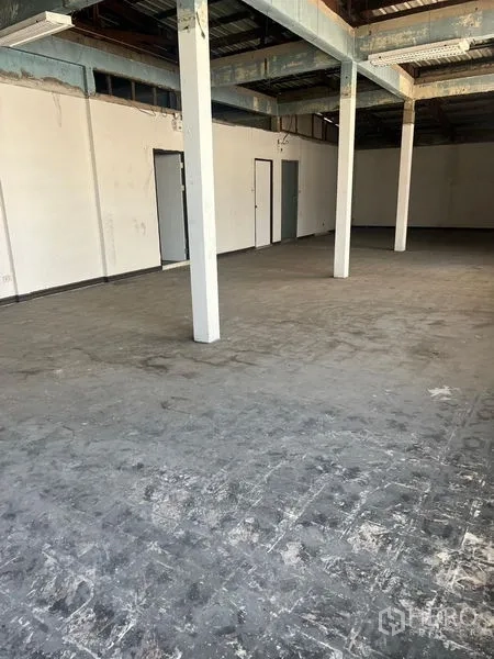 Shophouse for rent in Samphanthawong, Bangkok - Unfinished open floor with concrete surface, white pillars and metal roof beams.