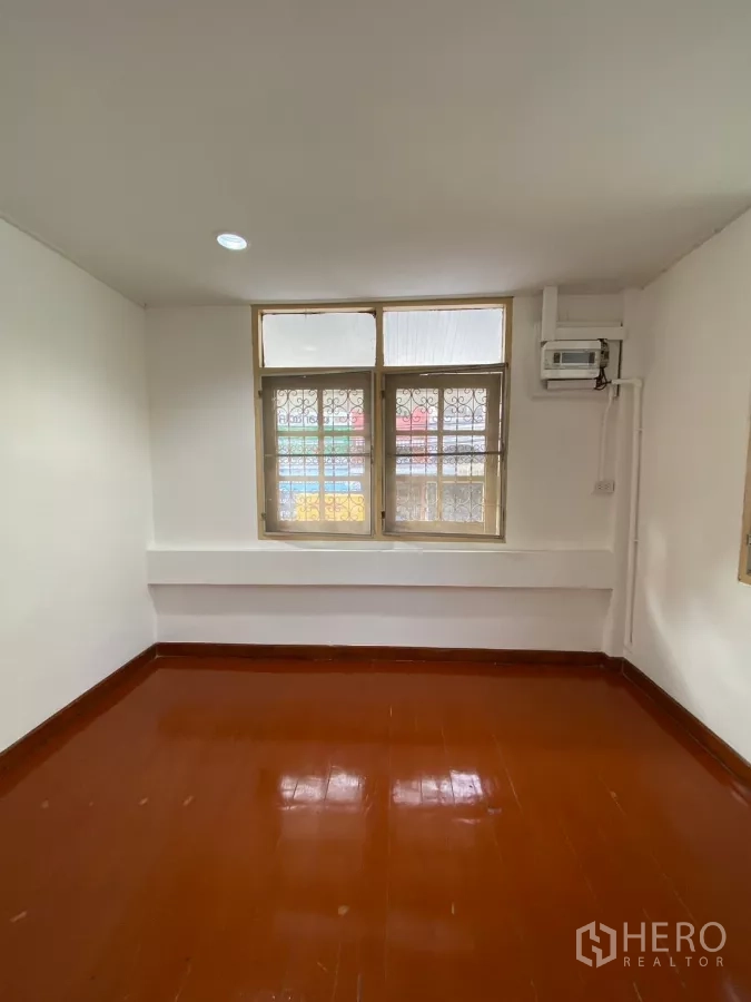 Detached House for rent in Bang Na, Bangkok - Bedroom with wooden flooring, window grilles and wall-mounted air conditioner.