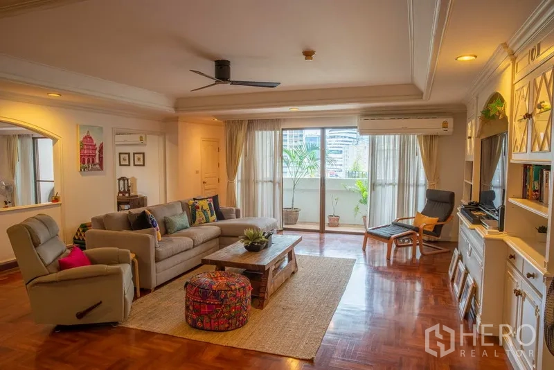 คอนโด ให้เช่าในKhlong Toei, Bangkok - ห้องนั่งเล่นโปร่งสบาย มีโซฟา บิวท์อิน ชั้นวาง และประตูกระจกสู่ระเบียงพร้อมวิวเมือง