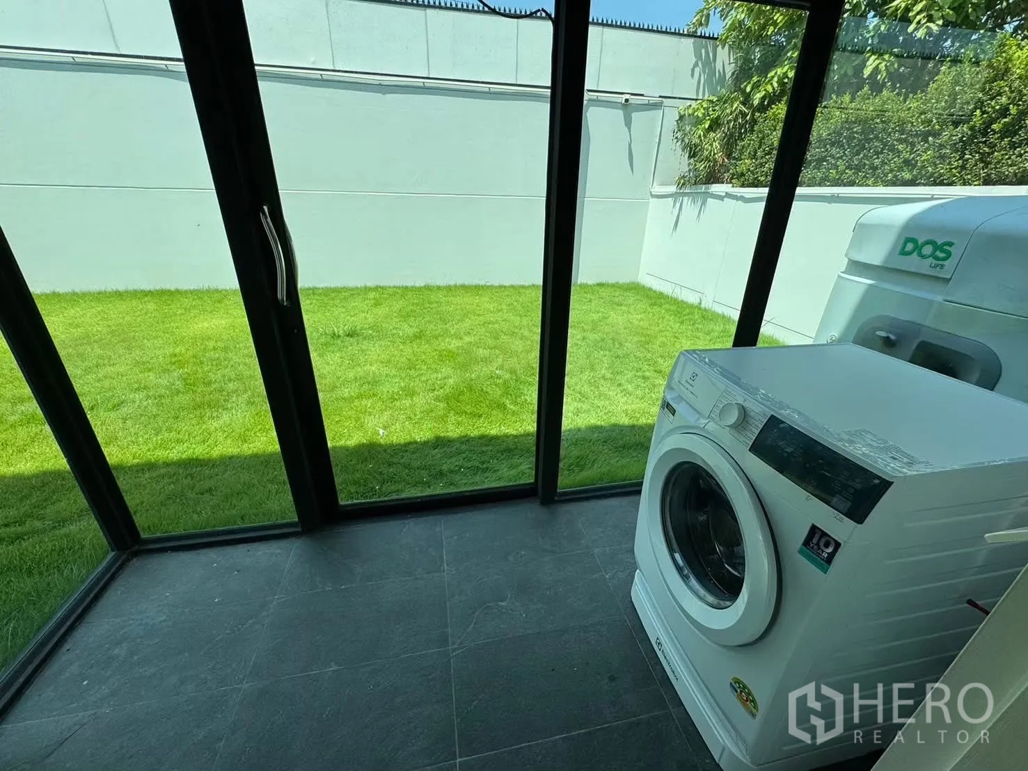 独栋房屋 for rent in Prawet, Bangkok - 玻璃洗衣房内有洗衣机，面向花园。