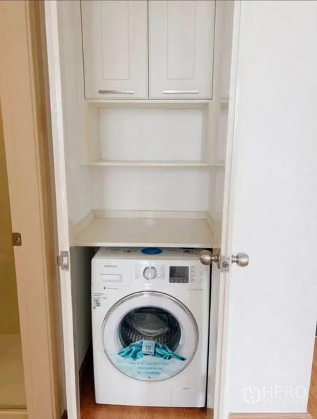 Condominium for rent in Watthana, Bangkok - In‑unit laundry closet with front‑load washing machine and shelves.