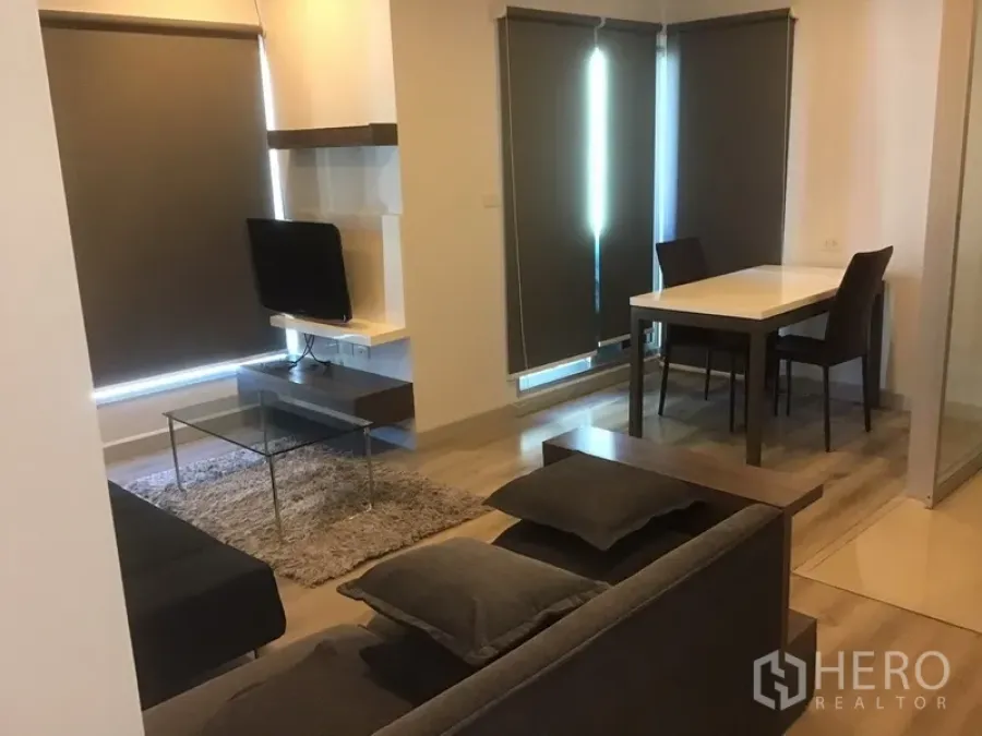 Condominium for rent in Sathon, Bangkok - Modern living and dining area with TV console, glass coffee table, shag rug and blackout blinds in a Sathorn condo.