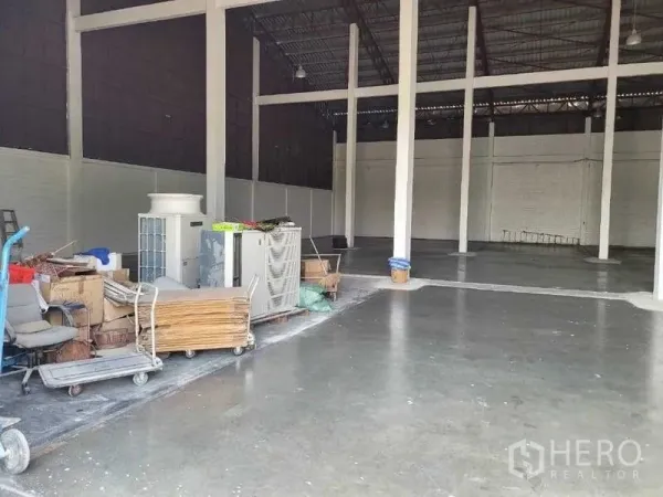Warehouse for rent in Phra Khanong, Bangkok - Open storage area with concrete floor and equipment carts to the side