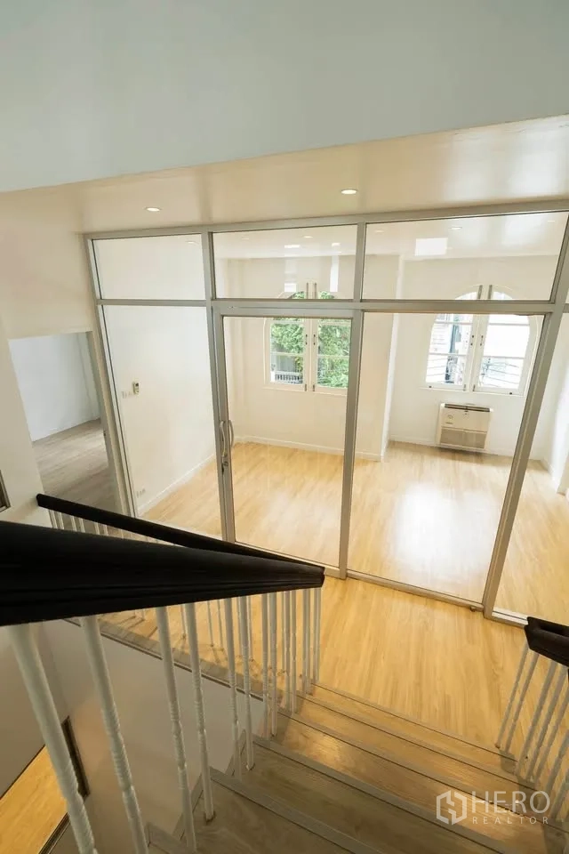 联排别墅 出租在Khlong Toei, Bangkok - 从楼梯俯视玻璃围合房间，日照充足。