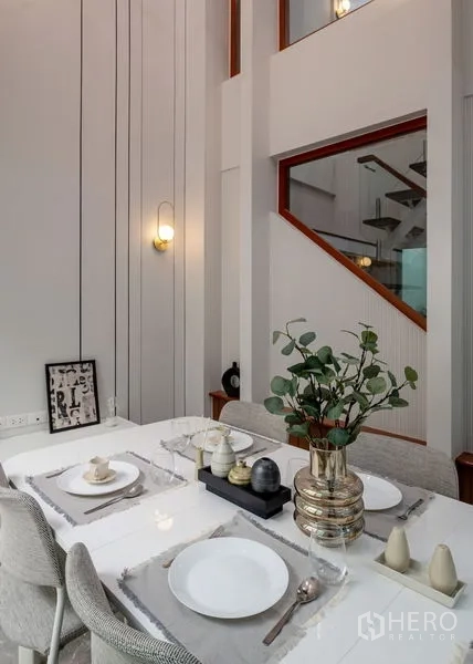 Townhouse for sale in Din Daeng, Bangkok - Styled dining table beside interior windows overlooking the staircase.