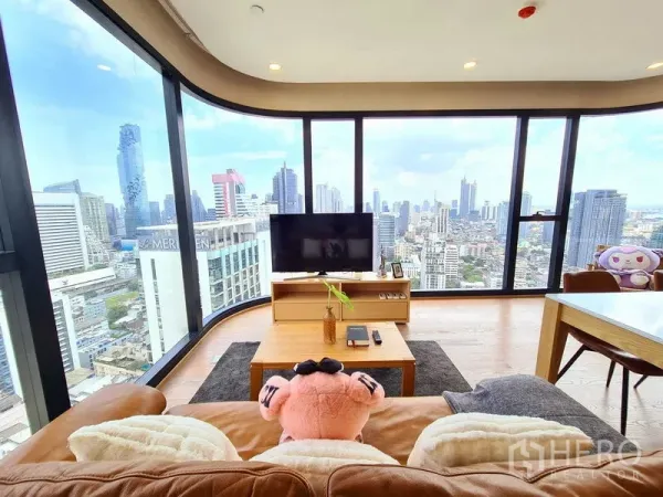 Condominium for rent in Bang Rak, Bangkok - Living room with floor-to-ceiling curved glass and sweeping Bangkok skyline view.