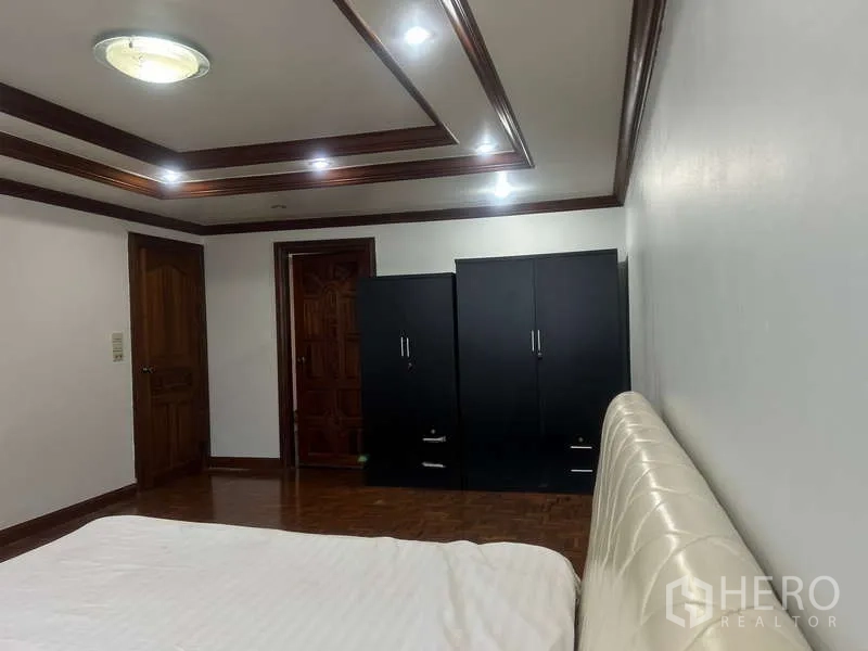 Condominium for sale in Huai Khwang, Bangkok - Bedroom corner with double wardrobes, wood doors, and recessed downlights.