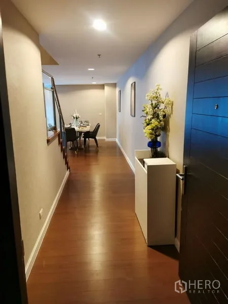 Condominium for rent or sale in Huai Khwang, Bangkok - Long entry hallway with wooden floors leading to the dining area.